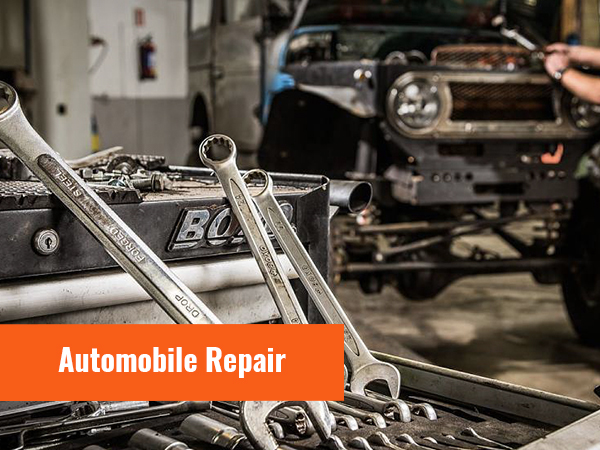 Autoreparatiescène met gereedschap en sleutels in focus. Op de achtergrond een technicus die aan een voertuig werkt.