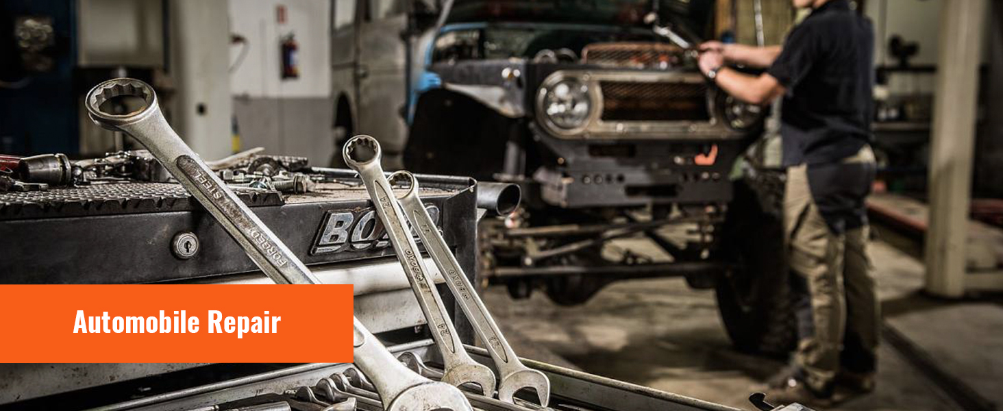 Autoreparatiescène met gereedschap en sleutels in focus. Op de achtergrond een technicus die aan een voertuig werkt.